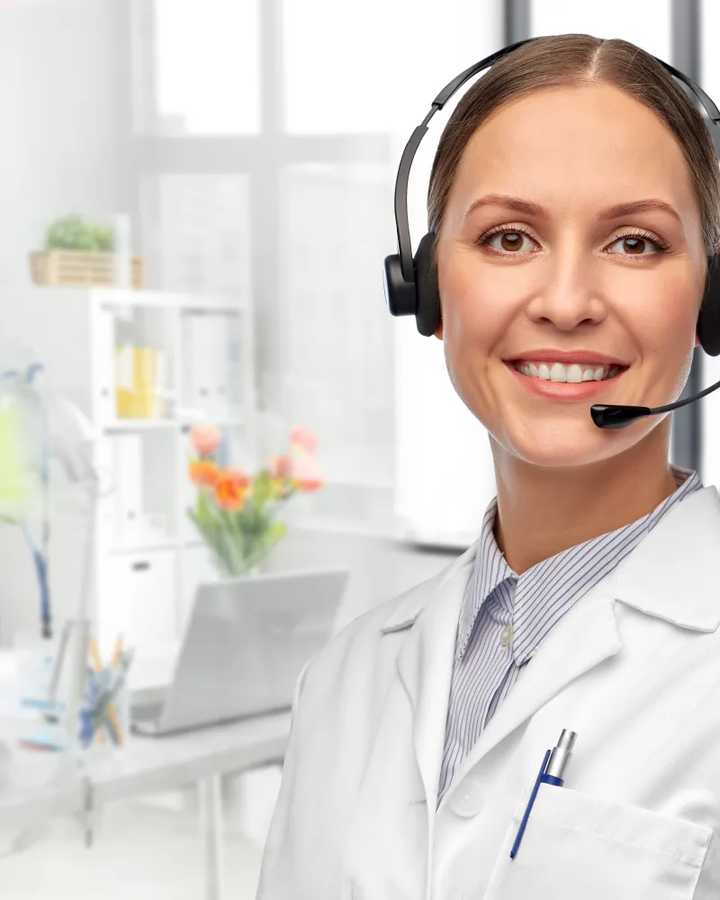 A smiling care coordinator wearing a headset in a bright clinic