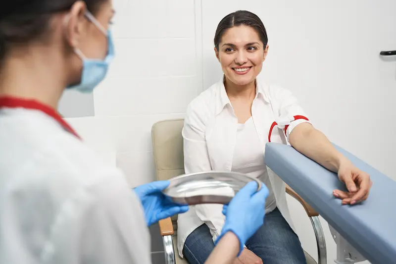A smiling woman relaxed as a nurse gets ready for her blood test