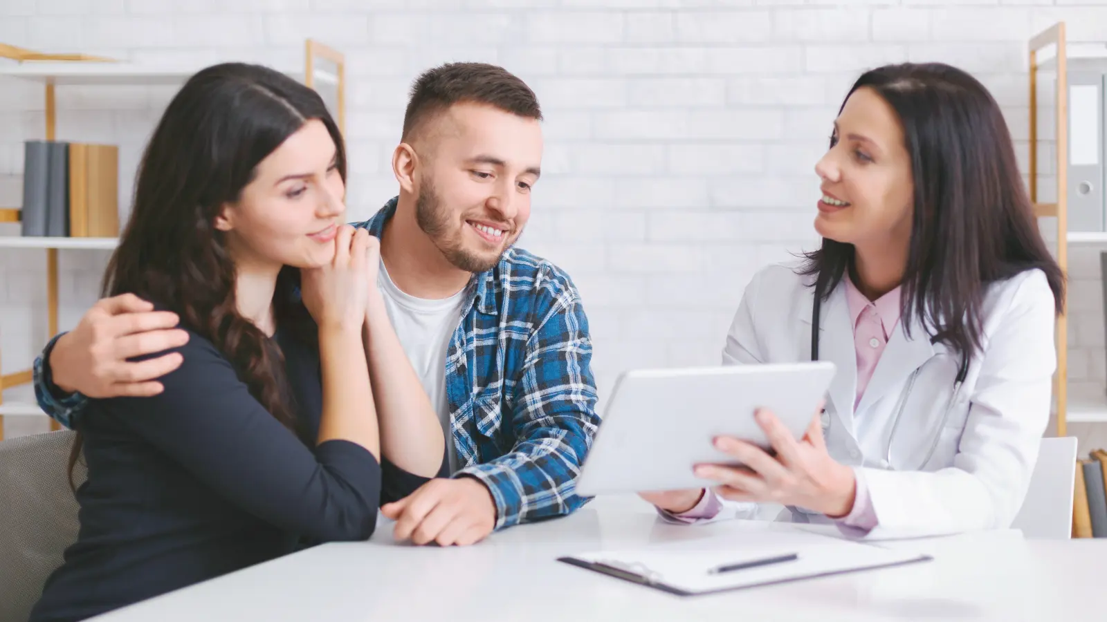 A couple listening closely as a doctor explains something on a tablet