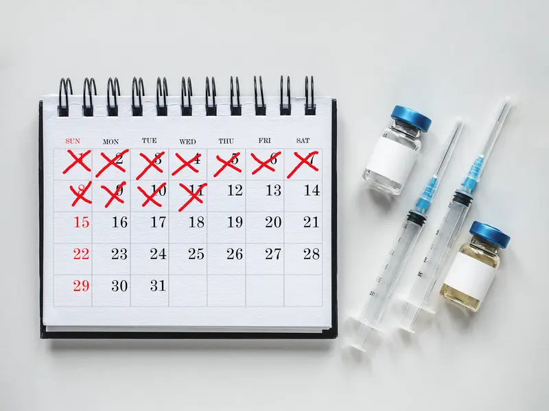 A calendar with the days ticked off beside medicine vials and syringes