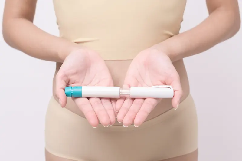 A woman holding a hormone injection pen, ready for her daily dose