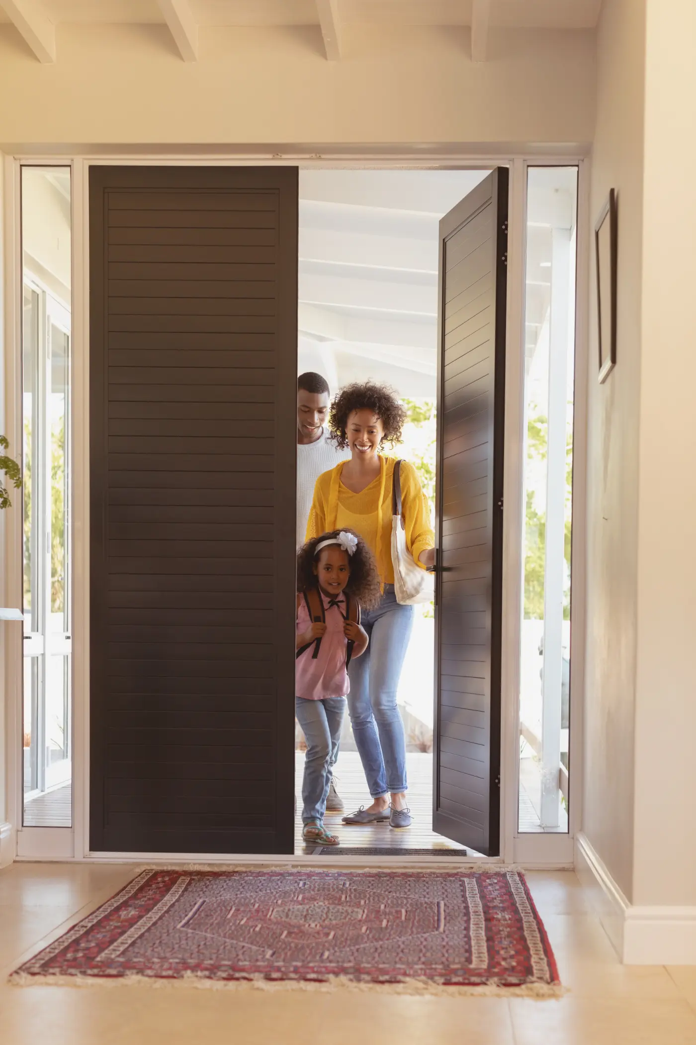 A family smiling as they step through their front door