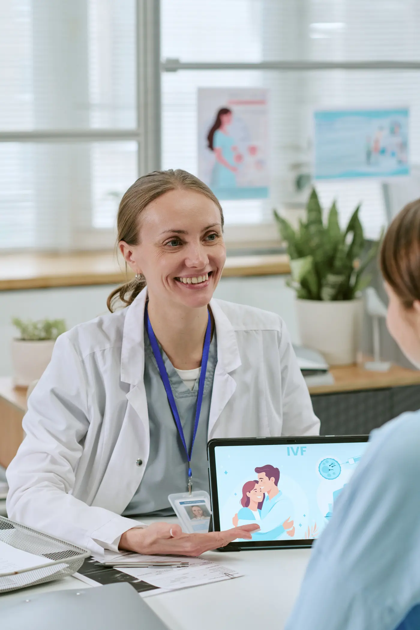 A smiling young clinician with a lanyard in a bright clinic