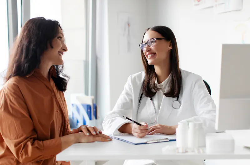 A woman talking and smiling with her doctor in a bright clinic