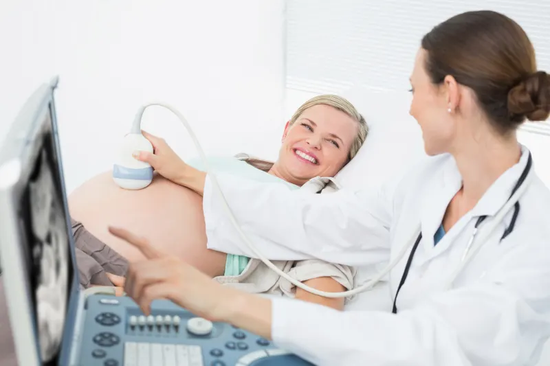 A doctor showing a smiling pregnant woman her baby on the ultrasound screen